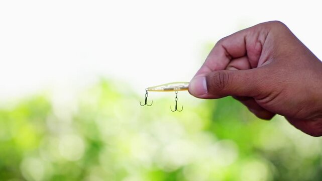 Treble hook yellow slip minnow fishing lure on blur background. Artificial fishing lure hold by hand showing on the camera.