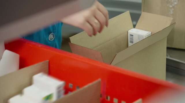 Organizing medication boxes in fast-paced pharmacy environment. Woman meticulously sorts medication boxes in pharmacy. Packages are efficiently moved to ensure timely access for customers. Close-up