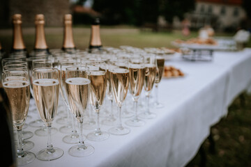 Cesis, Latvia - July 12, 2024 - A table set with champagne glasses and bottles, ready for a celebration or reception, with appetizers blurred in the background.