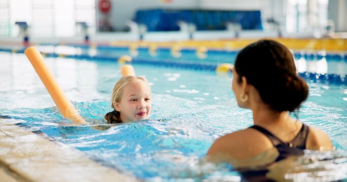 Instructor, active and girl in pool, swimming and woman with smile, proud and helping child in water. Lesson, happy and learning with teacher in school for training of kid, sports and teaching