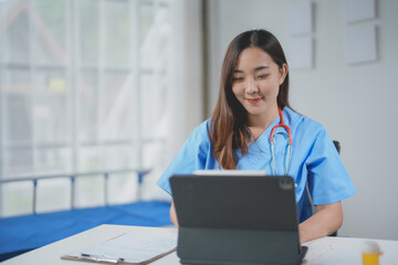 Young doctor is smiling while working with medical records on a digital tablet in a hospital room