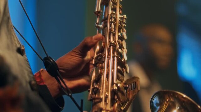 Close up view of hands of unrecognisable Black man playing saxophone at jazz concert with band