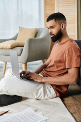 A stylish man focuses on his laptop in a relaxed home setting.