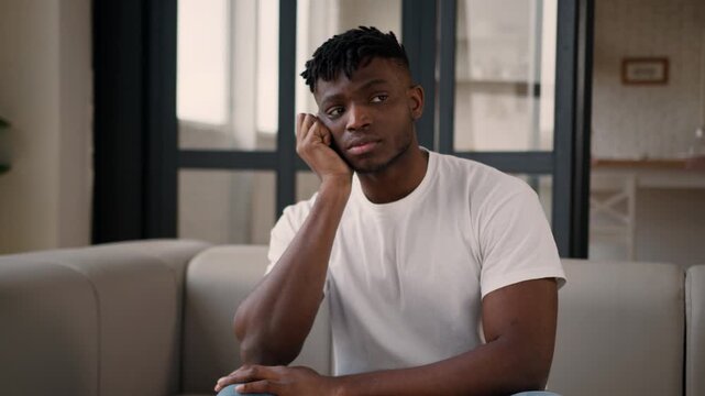 Sad African American man male homeowner tenant worried adult crisis stress in apartment loan mortgage problem credit debt eviction health insurance lonely ethnic guy upset tired exhausted on home sofa