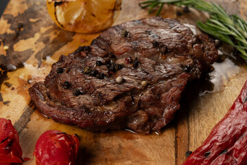 Closeup grilled Rib Eye Black Angus served with pepper and herbs on wooden background.