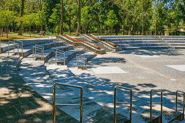 Modern amphitheater with stone stands and stairs with metal chrome railings in a park or city...
