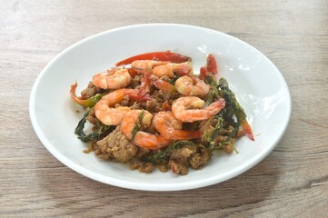 spicy stir fried chop pork with chili and basil leaf topping shrimp on plate  