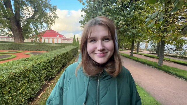 Beautiful young woman in ear muffs walking in the park in autumn. Enjoying the weather, smiling, breathing fresh air