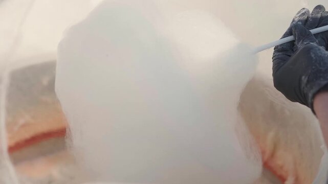 close-up of hand preparing cotton candy in machine outdoors