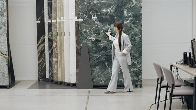 A woman walks through a spacious tile and porcelain stoneware store, exploring various elegant surfaces available for design projects