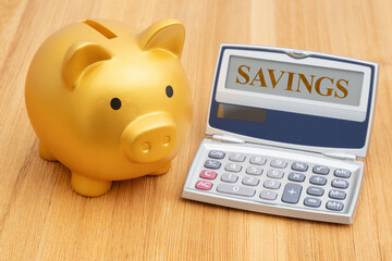 Saving money with a gold piggy bank with calculator on a desk