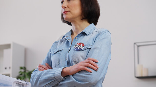 Woman standing proudly with a vote pin on her chest, fulfilling civic duty on election day