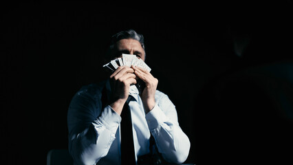 Corrupt policeman enjoying the smell of hundred-dollar bills he received as a bribe