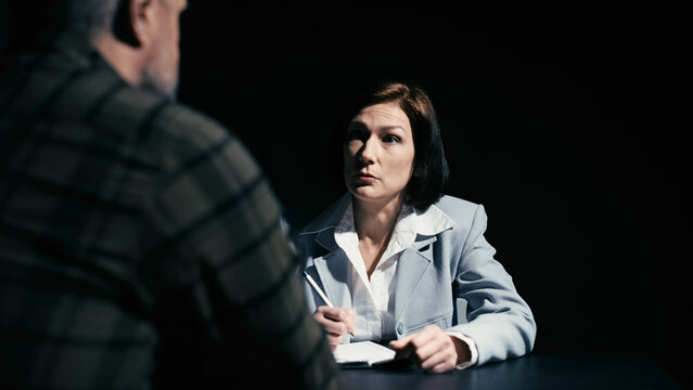 Female police detective questioning a male suspect in custody, interrogation room