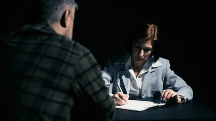 Woman detective writing down the testimony of a suspect indicted in a crime