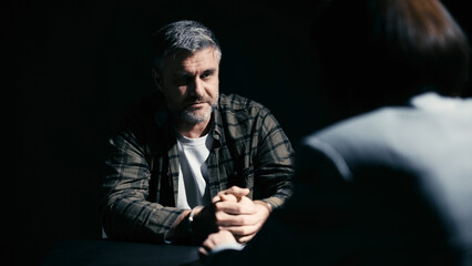 Middle-aged man in handcuffs listening to his attorney, preparing for interrogation with the detective