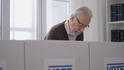 Elderly male citizen voting at a polling station, democratic elections, liberty