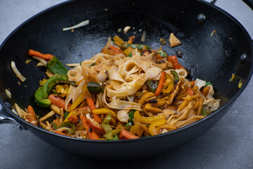Mixed vegetables and mushroom stir fry in cast iron wok along with white wheat noodles