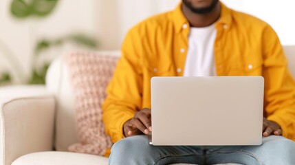 A man sitting on a couch with a laptop, filling out a detailed job application form online