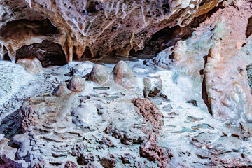 Underground rock formation with porous, irregular, rough and cracked walls due to water seepage in Neptune caves, illuminated with artificial light, Couvin, Wallonia, Belgium