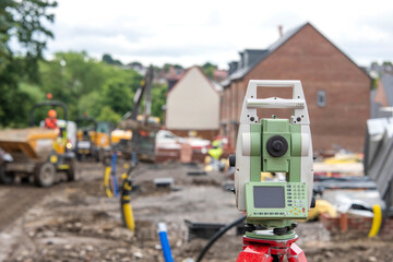 Construction Site Surveying Equipment With Workers and Heavy Machinery in Background