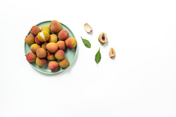 Juicy lychee fruit with cut in half and green leaves, top view. Fresh ripe tropical fruit
