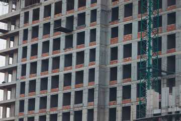 Fototapeta premium Construction of the facades of a residential modern building of concrete panels, close-up. Many new floors. Apartment building construction site with industrial scaffolding