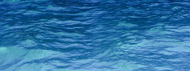 Blue green surface of the ocean with gentle ripples on the surface and light refracting. Natural background. The sea, the surface of the water. Close-up. Copy space