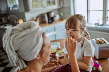 Mother and daughter having fun with chocolate spread in kitchen
