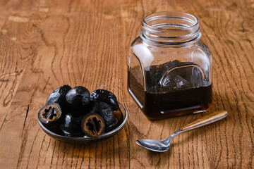 Saucer and jar with preserved walnuts on wooden background