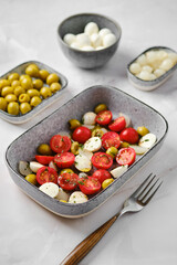 Mozzarella, tomato and olives salad seasoned with olive oil