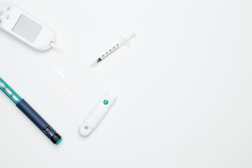 Obraz premium Diabetes concept with glucometer, syringe pen with insulin, blood test strips. Concept of worldwide diabetes awareness. Top view. Copy space