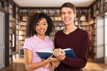 Happy young students in library with books