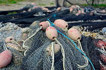 sieć rybacka z pływakami na brzegu, suszące sie na brzegu sieci rybackie z pływakami, fishing net on the shore, fishing net drying, Fishing net in the harbor, nets and floats are dried on the shore.
