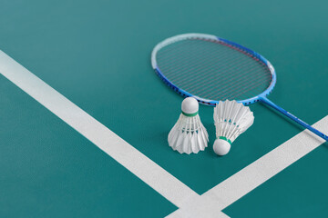 Cream white badminton shuttlecock and racket on floor in indoor badminton court, copy space, soft...