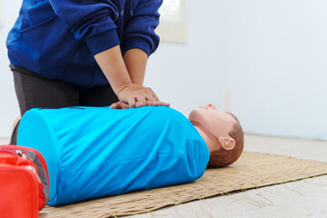 A woman performs chest compressions on a dummy during a CPR training class, demonstrating life-saving techniques and emergency response skills to ensure preparedness in critical situations.