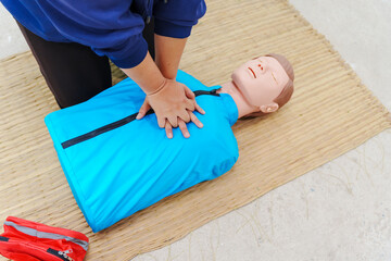 A woman performs chest compressions on a dummy during a CPR training class, demonstrating...