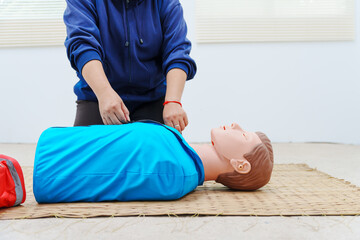 A woman performs chest compressions on a dummy during a CPR training class, demonstrating life-saving techniques and emergency response skills to ensure preparedness in critical situations.