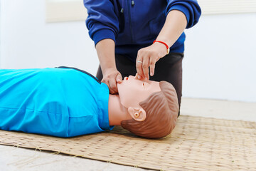 A woman performs chest compressions on a dummy during a CPR training class, demonstrating life-saving techniques and emergency response skills to ensure preparedness in critical situations.