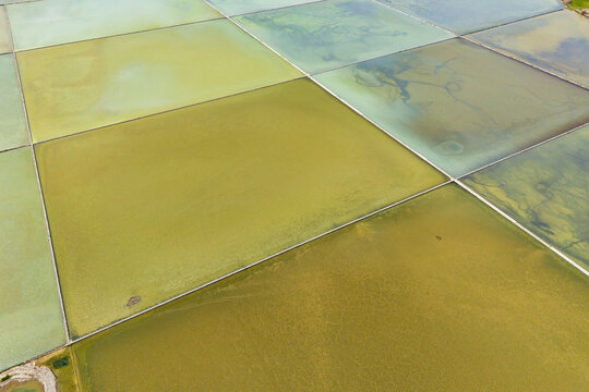 Sea salt evaporation saltern ponds filled with shallow water. Aerial drone view