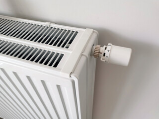 A white radiator thermostat for changing climatic conditions and temperature in a house, apartment, office, building against a white plastered wall