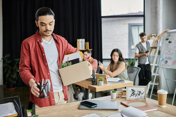Professionals gather in a modern workspace as layoffs take place, packing items.
