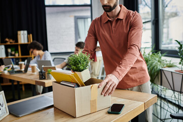 Dapper man packing his items during lay off, colleagues on backdrop.