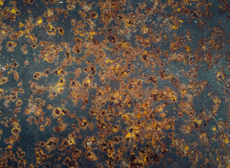 Brown, yellow and red rust on black metal surface closeup. Abstract texture. Corroded black metal background. Material oxidation concept.