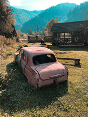An old abandoned car stands near a road in the mountains. Abandoned car concept