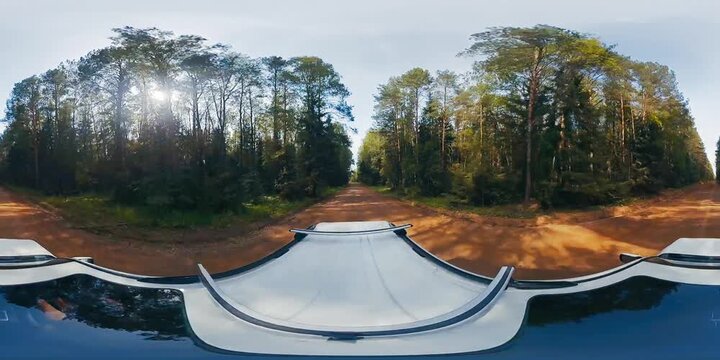 VR 360 footage of the car moving fast on an asphalt road in the forest at sunset