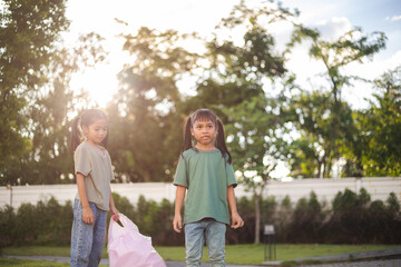 Obraz premium two young girls are picking up trash in a park