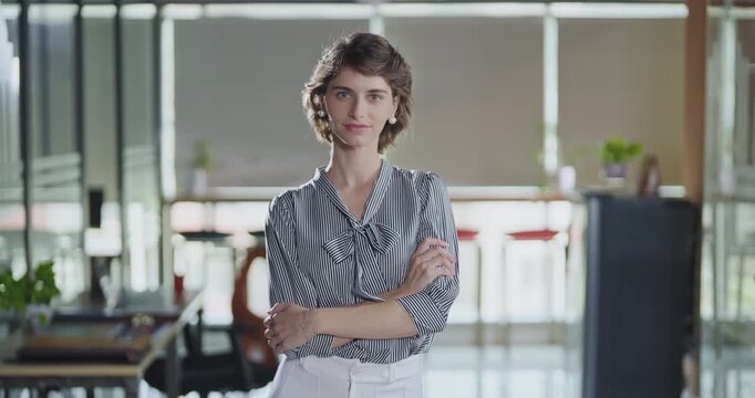 Young adult gen z cute girl agent boss standing proud fold hand look cam indoor job office happy french woman lady worker expert staff in formal dress cross arms do pose head shot video day work place