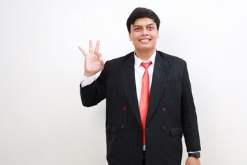 Successful smiling rich confident young asian businessman manager boss in formal suit wear showing okay gesture isolated in white background