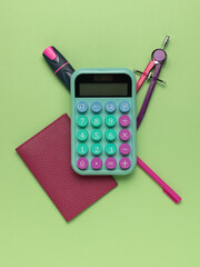 Colorful School Supplies: Calculator, Compass, Marker, Notebook on Green Background